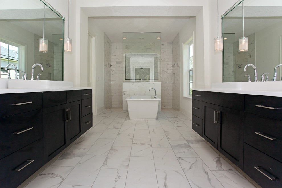 This is an example of a large transitional master bathroom in Jacksonville with a console sink, recessed-panel cabinets, dark wood cabinets, engineered quartz benchtops, a freestanding tub, a double shower, gray tile, stone tile, white walls and marble floors.