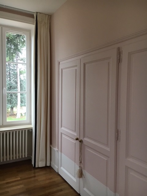 This is an example of a large transitional master bedroom in Lyon with pink walls and light hardwood floors.