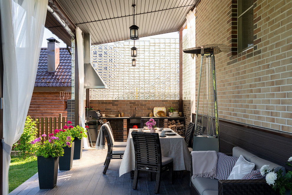 Cette image montre une terrasse arrière et au rez-de-chaussée méditerranéenne de taille moyenne avec une cuisine d'été, une extension de toiture et un garde-corps en matériaux mixtes.