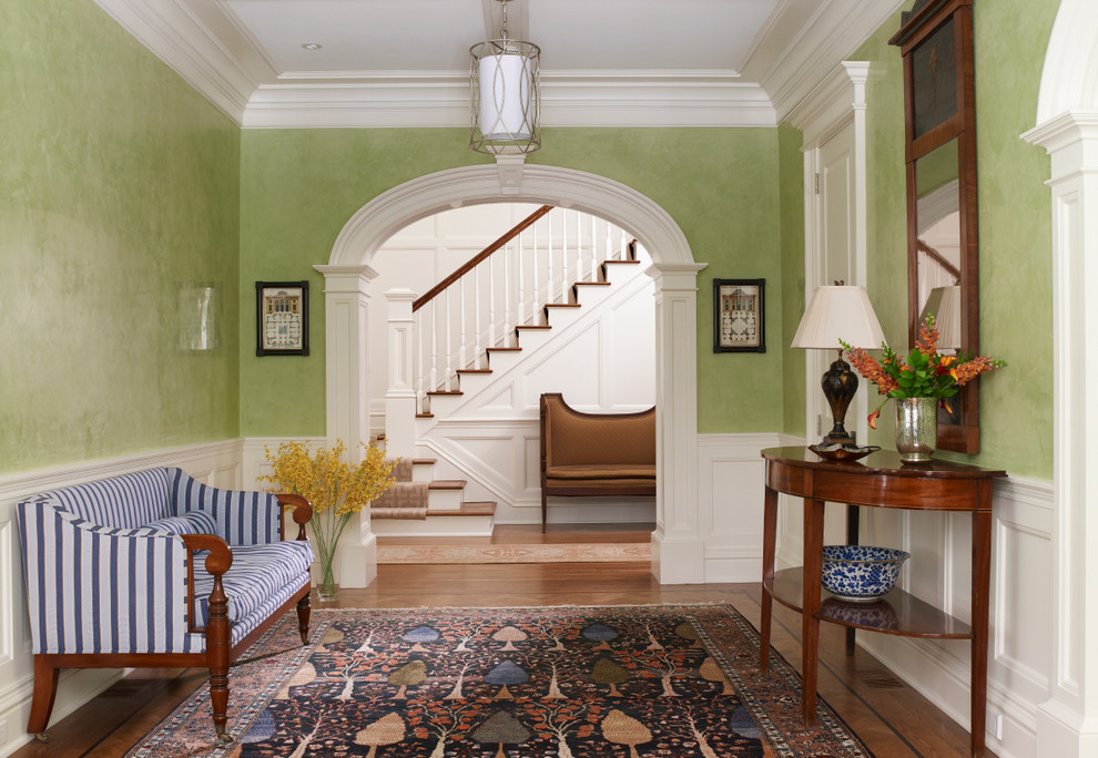 Photo of a large traditional foyer in New York with green walls and medium hardwood floors.