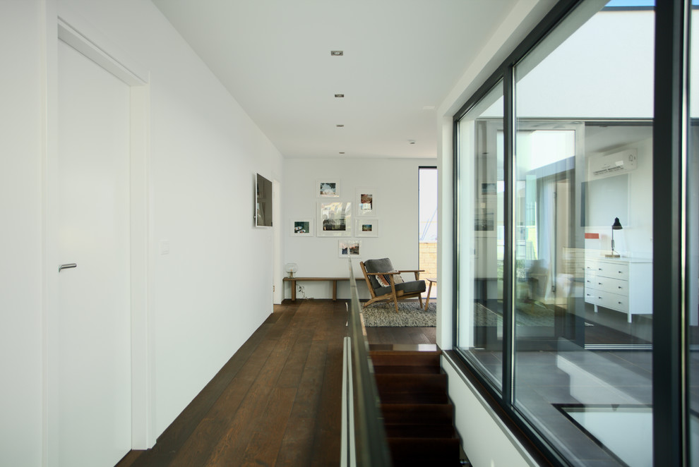 Kleiner Moderner Flur mit weißer Wandfarbe, braunem Holzboden und braunem Boden in München