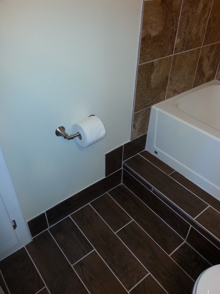 Example of a mid-sized transitional 3/4 porcelain tile and brown floor alcove bathtub design with furniture-like cabinets, dark wood cabinets, a two-piece toilet, white walls, an integrated sink, quartz countertops and white countertops