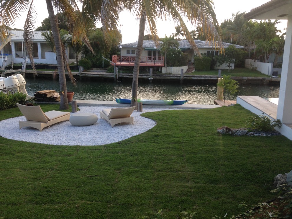 This is an example of an asian backyard rectangular infinity pool in Miami with gravel.