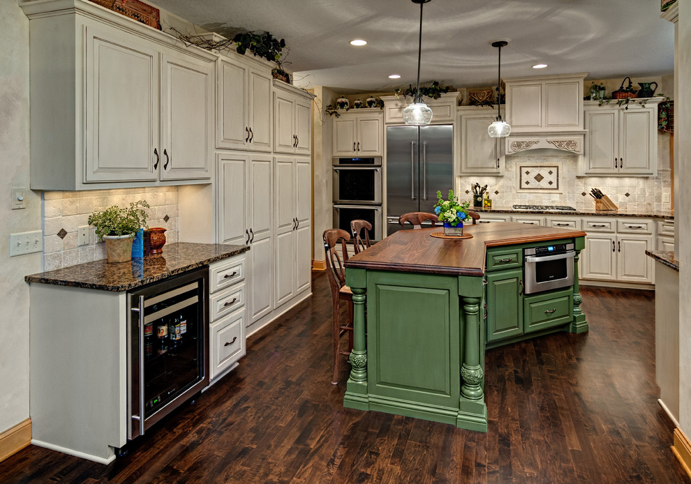 Traditional kitchen in Minneapolis with raised-panel cabinets, white cabinets, granite benchtops, beige splashback, stone tile splashback, stainless steel appliances, dark hardwood floors and with island.