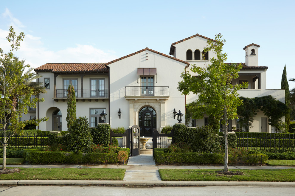 Expansive mediterranean two-storey stucco white house exterior in Houston with a gable roof and a tile roof.