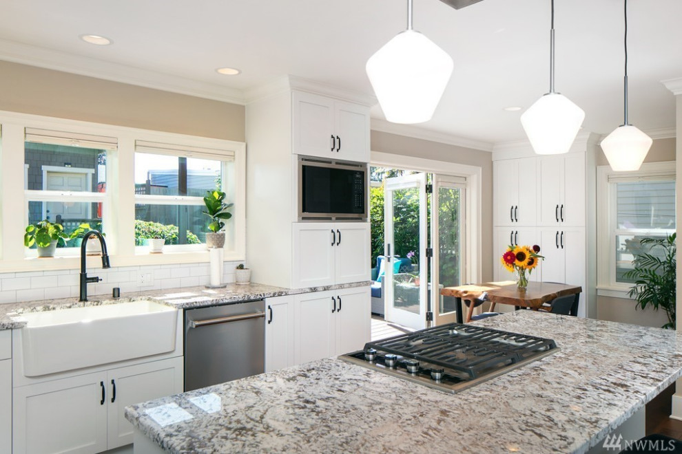 Mid-sized transitional l-shaped medium tone wood floor and brown floor eat-in kitchen photo in Seattle with a farmhouse sink, shaker cabinets, white cabinets, quartz countertops, white backsplash, ceramic backsplash, stainless steel appliances, an island and beige countertops