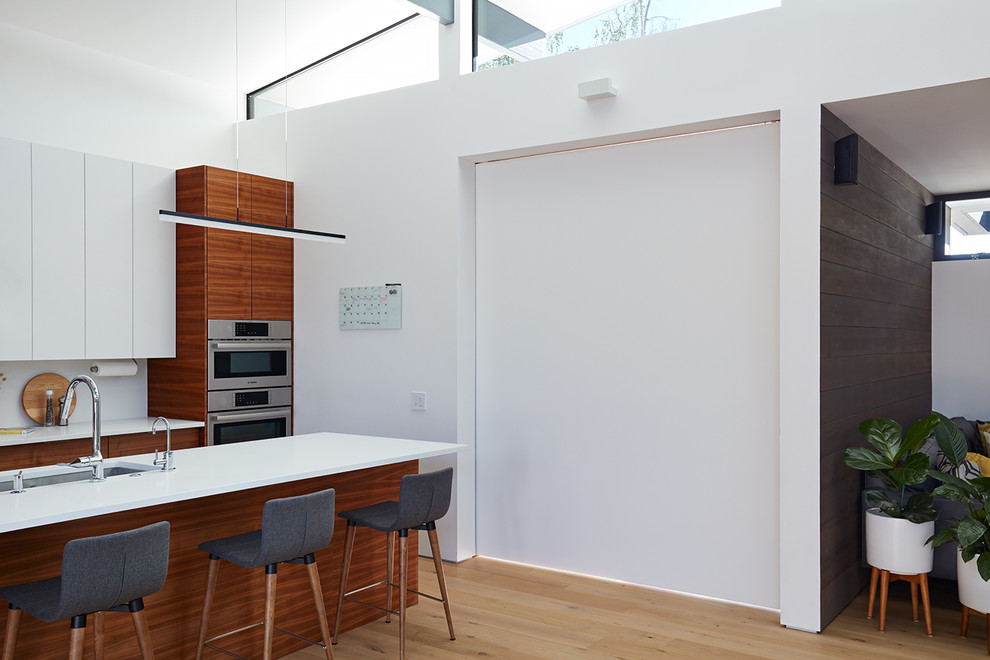 Los Altos New Residence - Klopf Architecture and Outer space Landscape Architects designed a new warm, modern, open, indoor-outdoor home in Los Altos, California. Inspired by mid-century modern homes but looking for something completely new and custom, the owners, a couple with two children, bought an older ranch style home with the intention of replacing it. 

Created on a grid, the house is designed to be at rest with differentiated spaces for activities; living, playing, cooking, dining and a piano space. The low-sloping gable roof over the great room brings a grand feeling to the space. The clerestory windows at the high sloping roof make the grand space light and airy. 
Upon entering the house, an open atrium entry in the middle of the house provides light and nature to the great room. The Heath tile wall at the back of the atrium blocks direct view of the rear yard from the entry door for privacy. 
The bedrooms, bathrooms, play room and the sitting room are under flat wing-like roofs that balance on either side of the low sloping gable roof of the main space. Large sliding glass panels and pocketing glass doors foster openness to the front and back yards. In the front there is a fenced-in play space connected to the play room, creating an indoor-outdoor play space that could change in use over the years. The play room can also be closed off from the great room with a large pocketing door. In the rear, everything opens up to a deck overlooking a pool where the family can come together outdoors.
Wood siding travels from exterior to interior, accentuating the indoor-outdoor nature of the house. Where the exterior siding doesn’t come inside, a palette of white oak floors, white walls, walnut cabinetry, and dark window frames ties all the spaces together to create a uniform feeling and flow throughout the house. The custom cabinetry matches the minimal joinery of the rest of the house, a trim-less, minimal appearance. Wood siding was mitered in the corners, including where siding meets the interior drywall. Wall materials were held up off the floor with a minimal reveal. This tight detailing gives a sense of cleanliness to the house. 
The garage door of the house is completely flush and of the same material as the garage wall, de-emphasizing the garage door and making the street presentation of the house kinder to the neighborhood.
The house is akin to a custom, modern-day Eichler home in many ways. Inspired by mid-century modern homes with today’s materials, approaches, standards, and technologies. The goals were to create an indoor-outdoor home that was energy-efficient, light and flexible for young children to grow. This 3,000 square foot, 3 bedroom, 2.5 bathroom new house is located in Los Altos in the heart of the Silicon Valley. 


Klopf Architecture Project Team: John Klopf, AIA, and Chuang-Ming Liu
 Landscape Architect: Outer space Landscape Architects
 Structural Engineer: ZFA Structural Engineers
 Staging: Da Lusso Design 
 Photography ©2018 Mariko Reed
 Location: Los Altos, CA 
Year completed: 2017