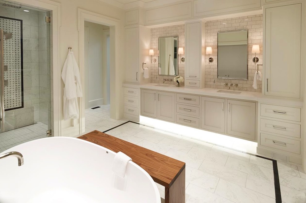 This is an example of a large transitional master bathroom in Salt Lake City with recessed-panel cabinets, white cabinets, a freestanding tub, an alcove shower, white tile, marble, white walls, marble floors, an undermount sink, solid surface benchtops, white floor and a hinged shower door.