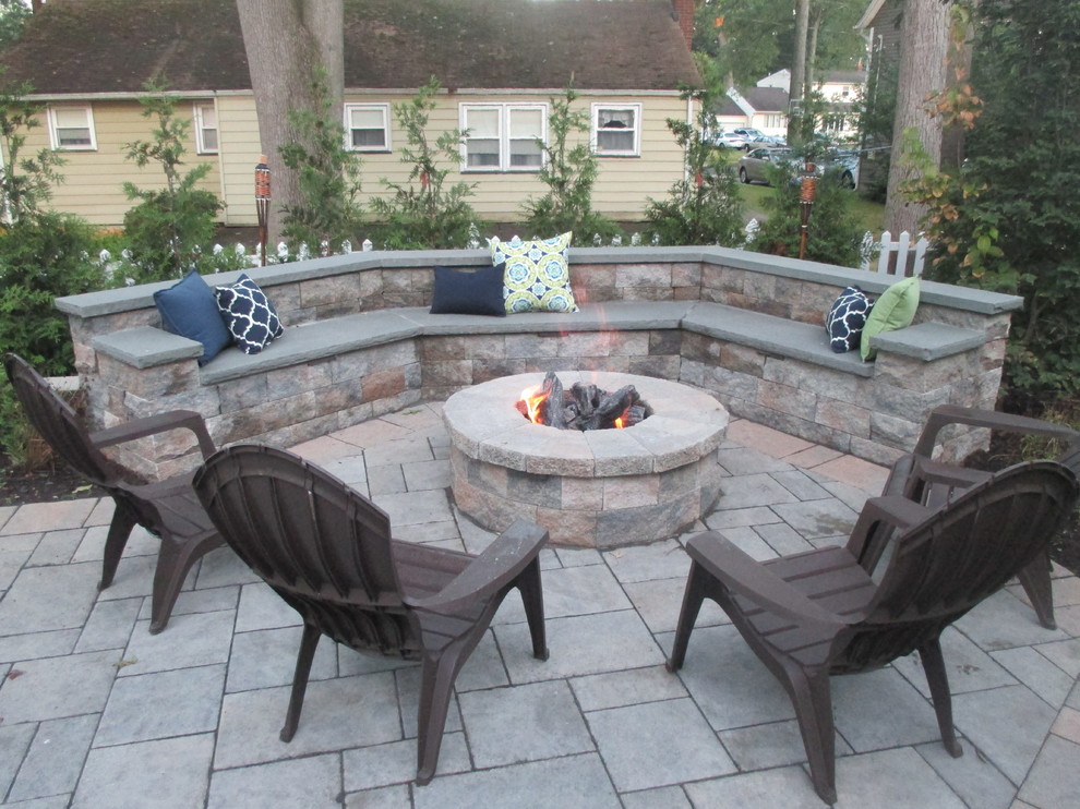 This is an example of a large traditional backyard patio in New York with a fire feature, no cover and concrete pavers.