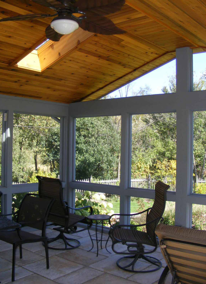Cette photo montre un porche d'entrée de maison arrière chic de taille moyenne avec une moustiquaire, des pavés en pierre naturelle, une extension de toiture et un garde-corps en verre.