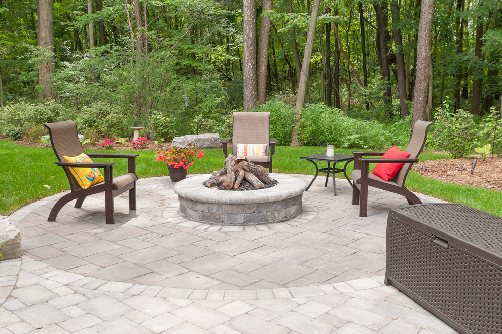 Large eclectic backyard patio in Grand Rapids with a fire feature and brick pavers.