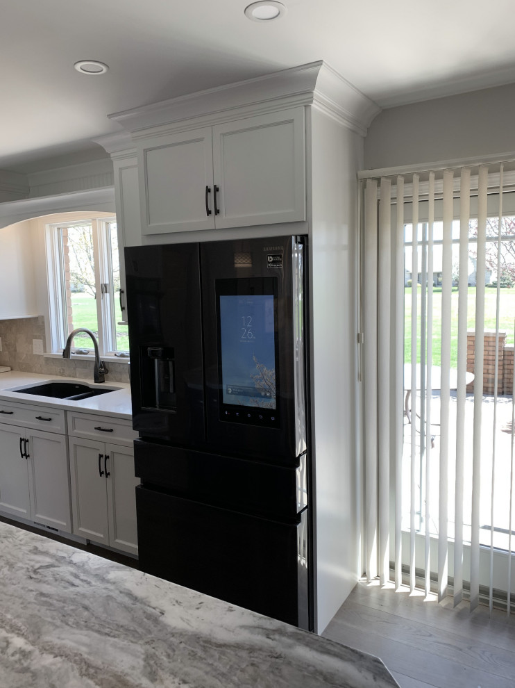 Eat-in kitchen - large transitional l-shaped vinyl floor and gray floor eat-in kitchen idea with an undermount sink, recessed-panel cabinets, white cabinets, quartz countertops, gray backsplash, ceramic backsplash, stainless steel appliances, an island and white countertops