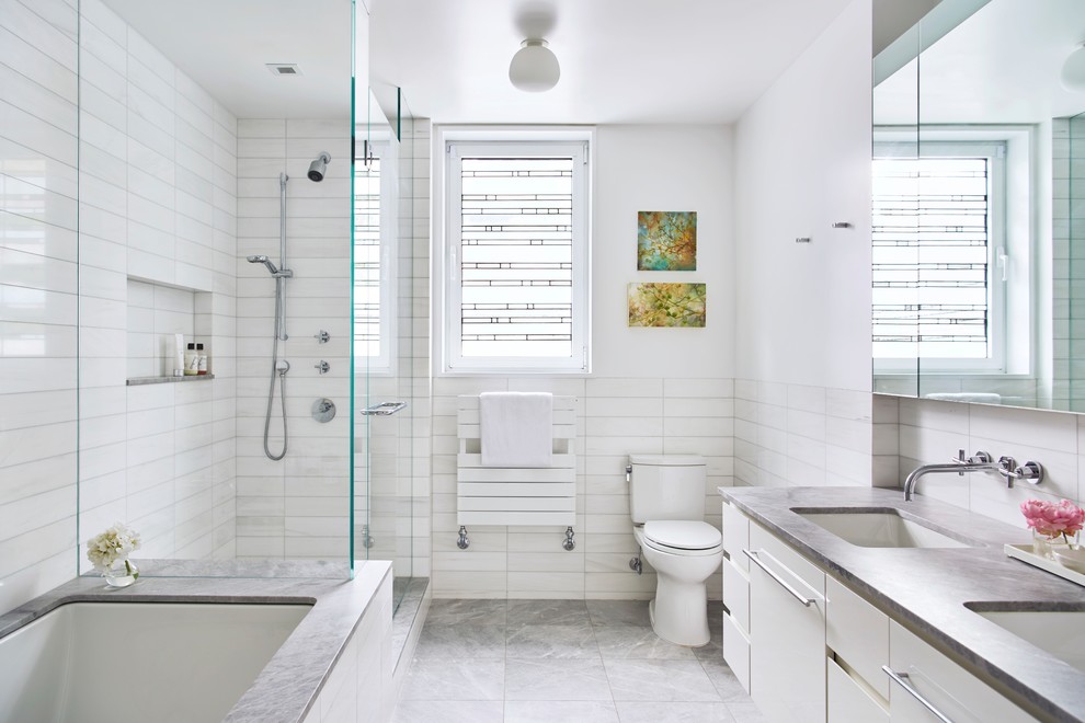 Design ideas for a contemporary master bathroom in New York with white cabinets, an undermount tub, a corner shower, white tile, ceramic tile, white walls, ceramic floors, an undermount sink, engineered quartz benchtops, grey floor, a hinged shower door, flat-panel cabinets, grey benchtops and a two-piece toilet.