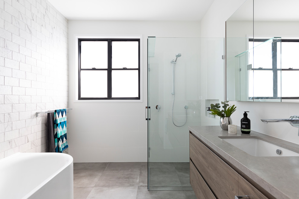 Mid-sized contemporary 3/4 bathroom in Brisbane with medium wood cabinets, a corner tub, a corner shower, a one-piece toilet, white tile, ceramic tile, white walls, cement tiles, an undermount sink, engineered quartz benchtops, grey floor, a hinged shower door, grey benchtops and flat-panel cabinets.