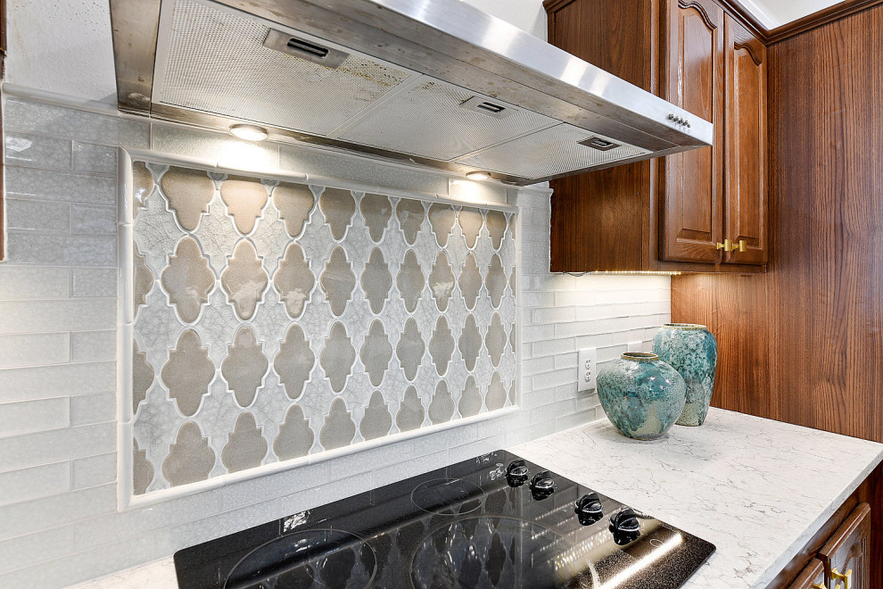 Example of a mid-sized transitional ceramic tile and white floor eat-in kitchen design with an undermount sink, raised-panel cabinets, dark wood cabinets, quartz countertops, white backsplash, glass tile backsplash, stainless steel appliances, an island and white countertops
