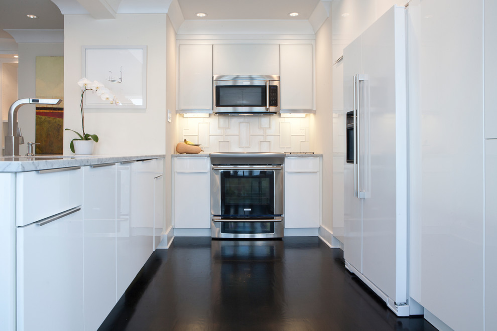 Inspiration for a small transitional u-shaped dark wood floor and brown floor enclosed kitchen remodel with a single-bowl sink, flat-panel cabinets, white cabinets, marble countertops, white backsplash, porcelain backsplash, stainless steel appliances and no island