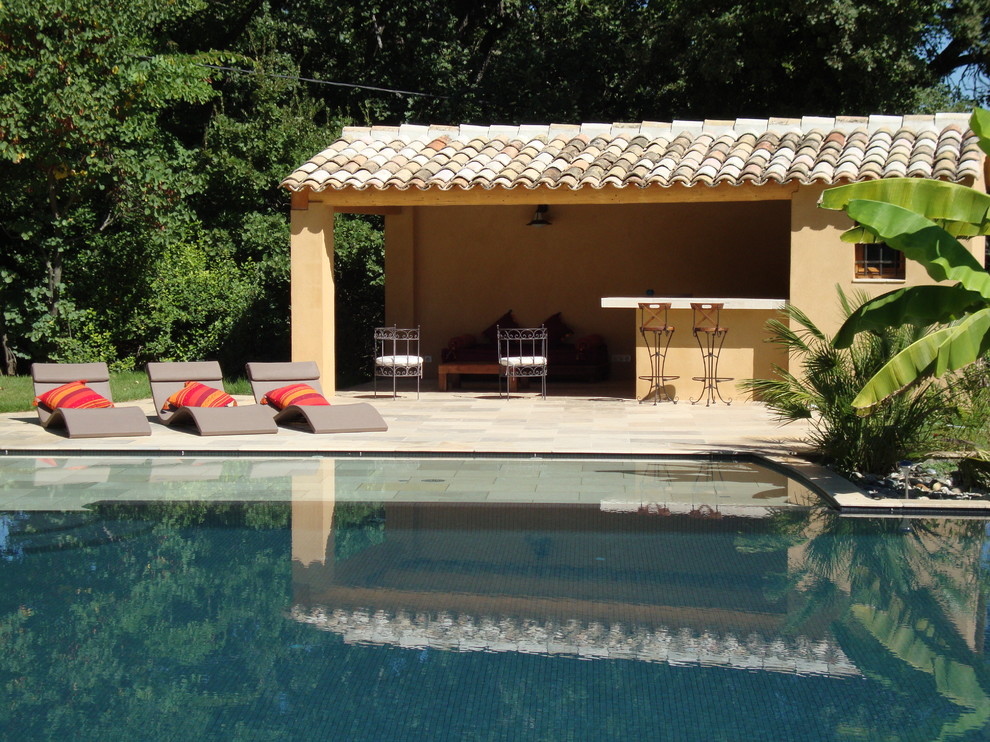 This is an example of a mid-sized mediterranean backyard pool in Marseille with natural stone pavers.