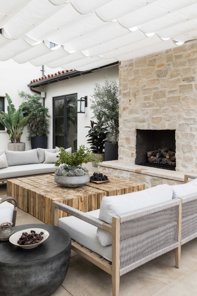 Inspiration for a beach style patio in Orange County with with fireplace and an awning.