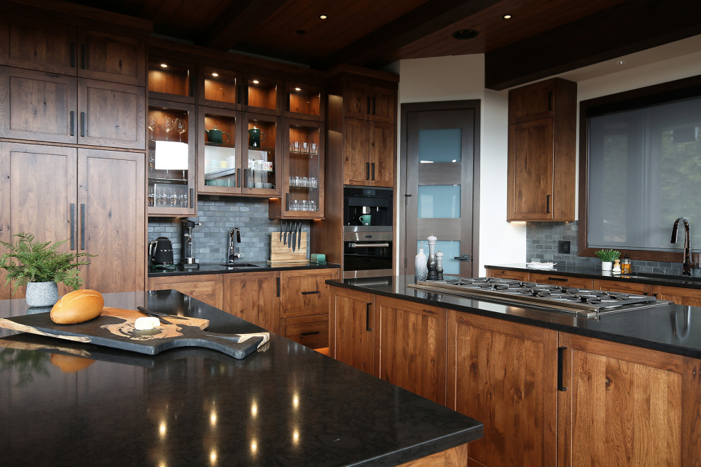 Open concept kitchen - large rustic u-shaped medium tone wood floor, brown floor and exposed beam open concept kitchen idea with an undermount sink, shaker cabinets, medium tone wood cabinets, quartz countertops, gray backsplash, slate backsplash, stainless steel appliances, two islands and black countertops