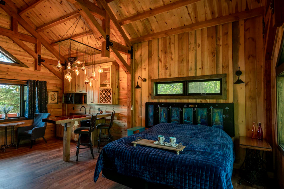 Aménagement d'une petite chambre parentale montagne avec un sol en bois brun, un plafond voûté et du lambris de bois.