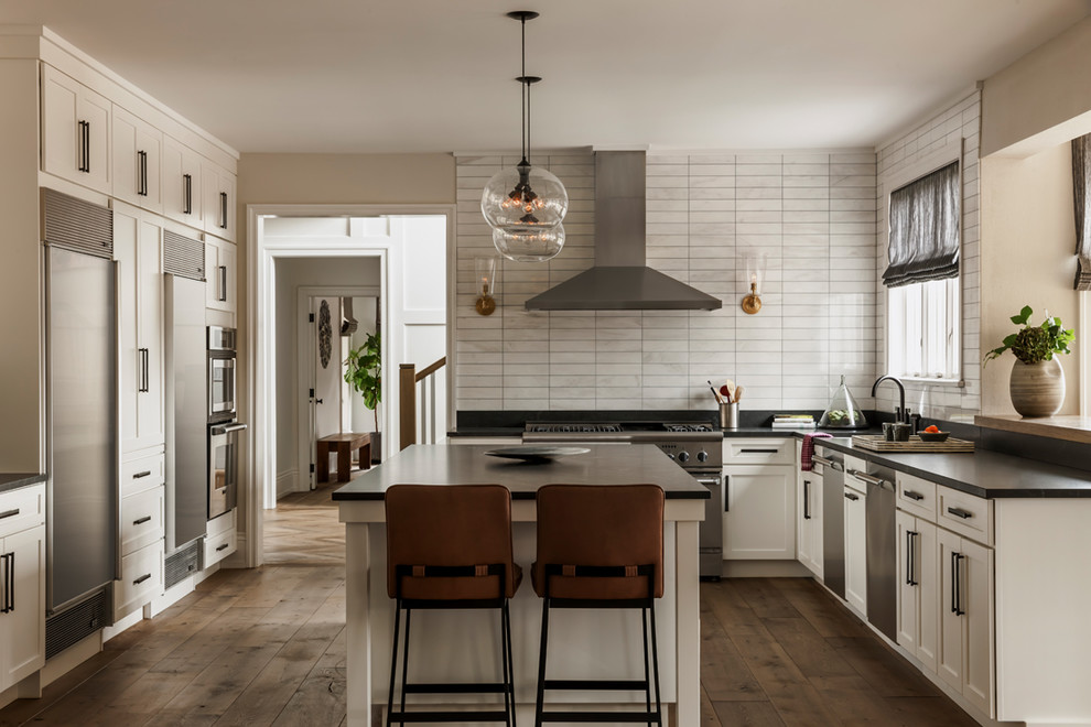 Design ideas for a transitional l-shaped kitchen in Philadelphia with shaker cabinets, white cabinets, white splashback, stainless steel appliances, dark hardwood floors, with island and brown floor.