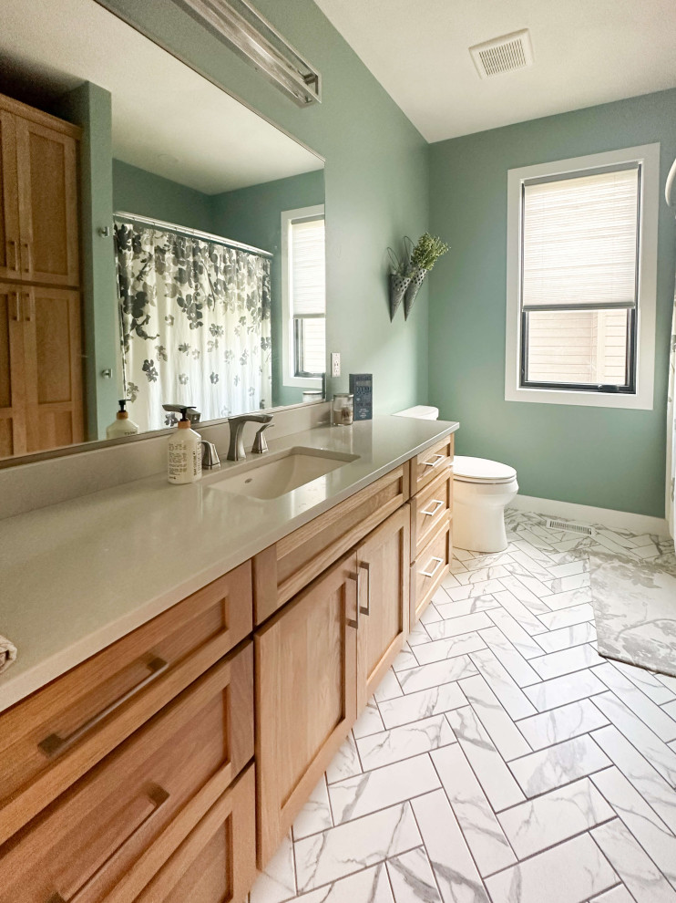 Photo of a medium sized classic family bathroom in Other with shaker cabinets, brown cabinets, an alcove bath, a shower/bath combination, a one-piece toilet, green walls, porcelain flooring, a submerged sink, engineered stone worktops, white floors, a shower curtain, beige worktops, a wall niche, a single sink and a built in vanity unit.