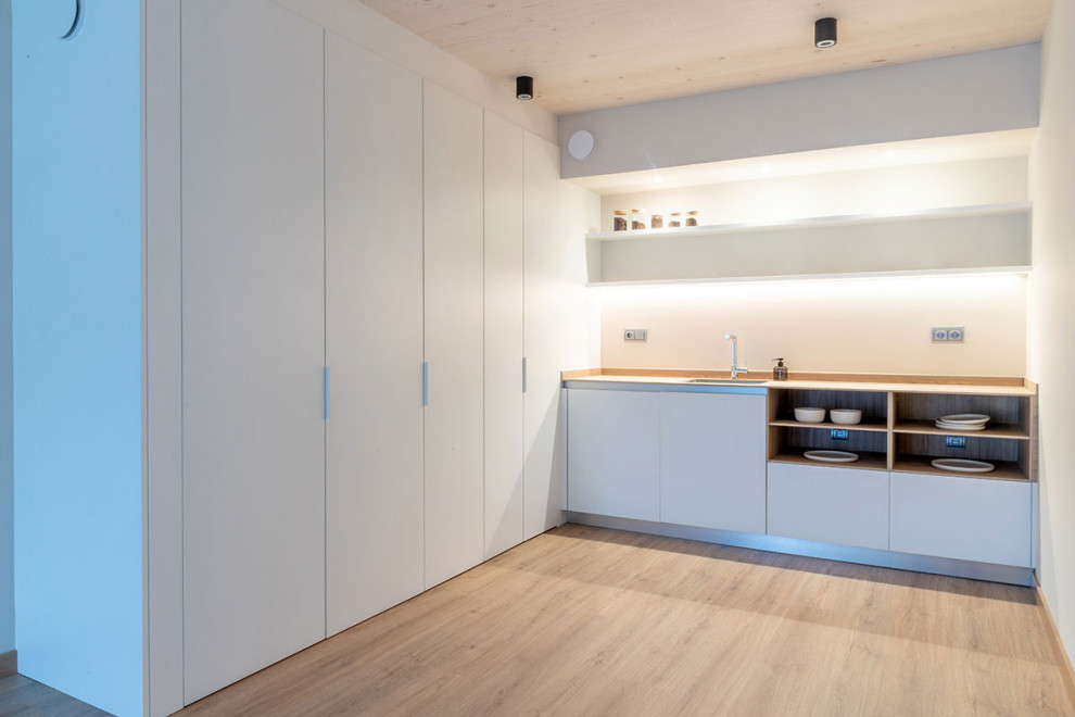 Esempio di una cucina moderna con ante lisce, ante grigie, pavimento in legno massello medio, penisola e pavimento marrone