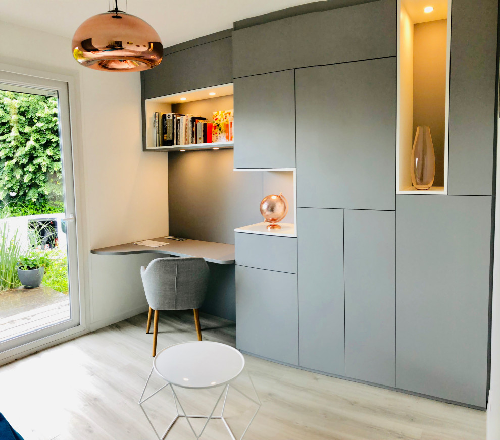 Photo of a mid-sized contemporary home office in Paris with a library, grey walls, vinyl floors, no fireplace, a freestanding desk and beige floor.
