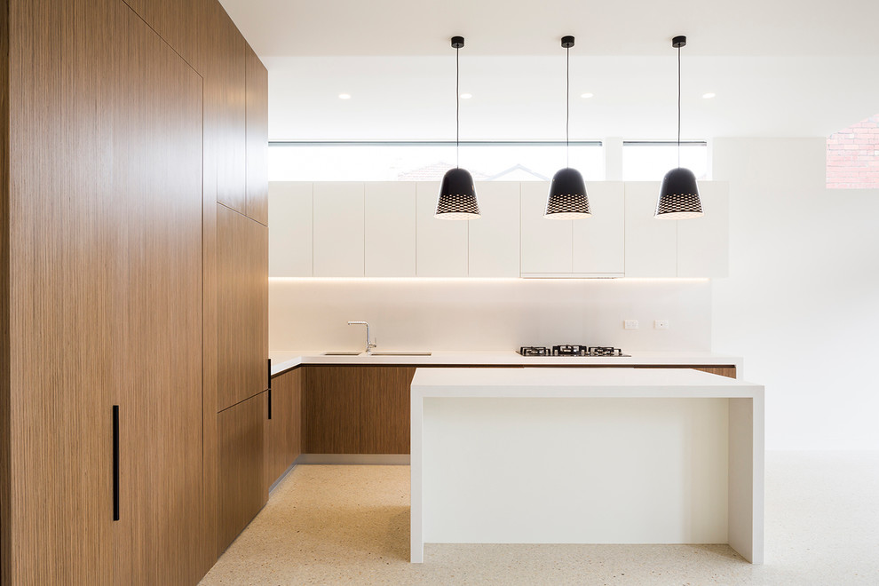 This is an example of a mid-sized contemporary l-shaped kitchen in Melbourne with a double-bowl sink, flat-panel cabinets, medium wood cabinets, white splashback, panelled appliances and with island.