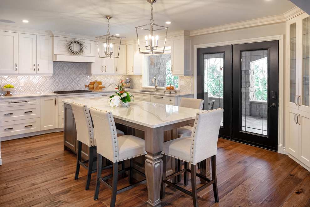 Kitchen pantry - transitional u-shaped kitchen pantry idea with an undermount sink, shaker cabinets, white cabinets, quartz countertops, beige backsplash, an island and beige countertops