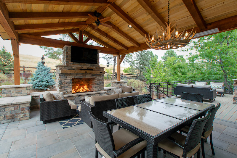 Inspiration for a large country backyard patio in Denver with with fireplace, concrete pavers and a roof extension.