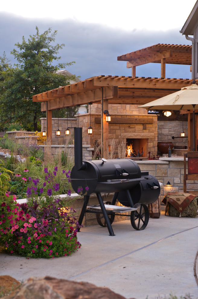 Mid-sized country backyard patio in Kansas City with an outdoor kitchen, concrete slab and a pergola.