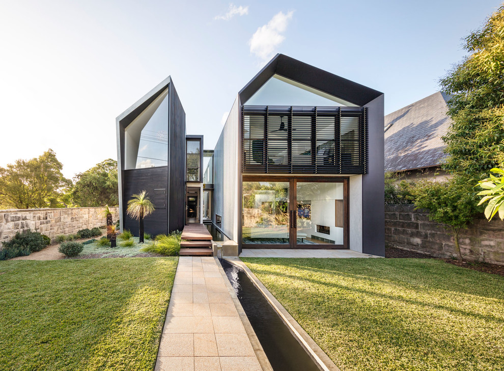 Photo of a contemporary two-storey black house exterior in Sydney with metal siding, a metal roof and a gable roof.