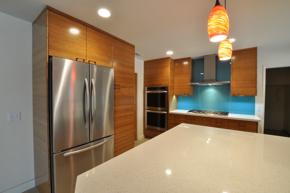 Design ideas for a mid-sized modern u-shaped open plan kitchen in Los Angeles with an undermount sink, flat-panel cabinets, medium wood cabinets, quartz benchtops, blue splashback, glass sheet splashback, stainless steel appliances, porcelain floors and with island.