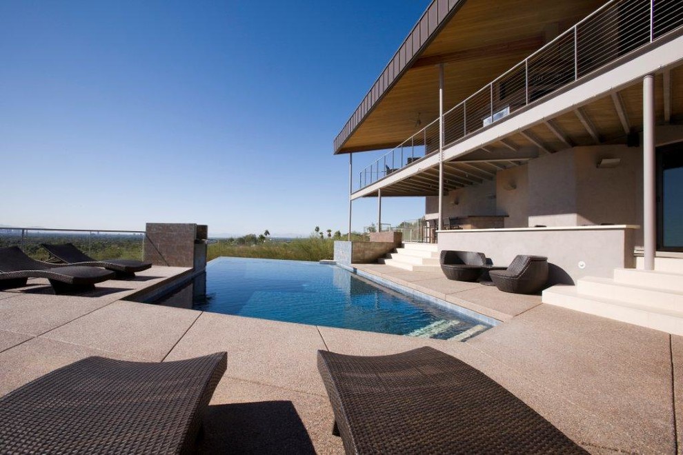 Large backyard custom-shaped infinity pool fountain photo in Phoenix with decking
