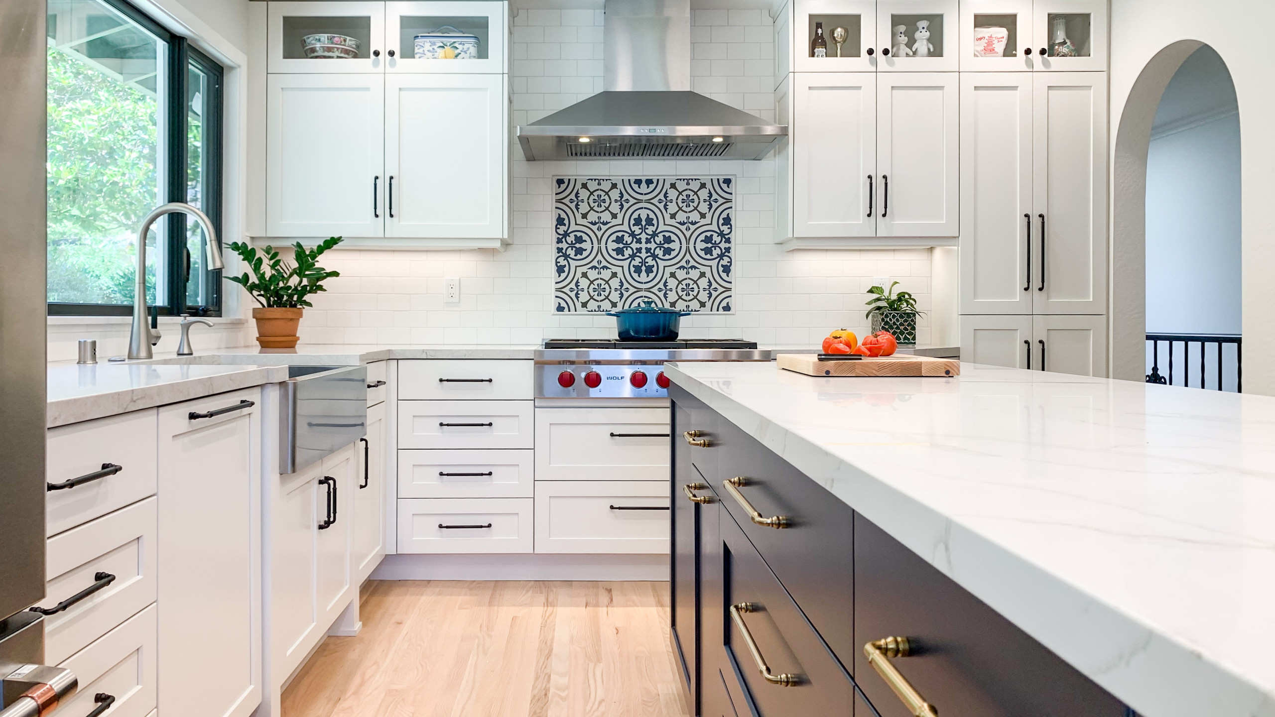 white and blue custom kitchen with a decorative backsplash and gold and black hardware