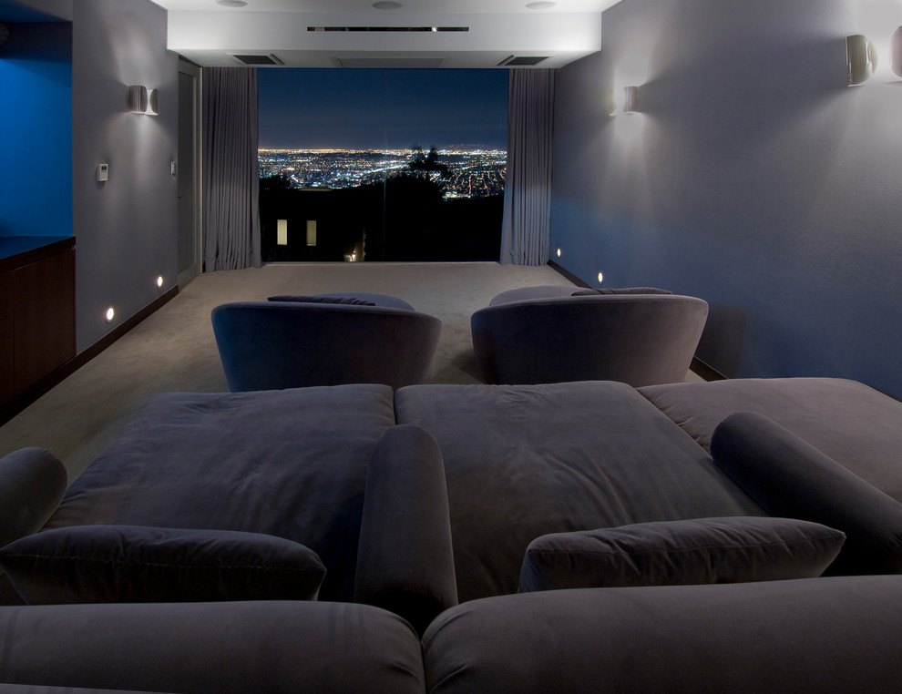 This is an example of a large modern enclosed home theatre in Los Angeles with carpet, a wall-mounted tv and grey floor.