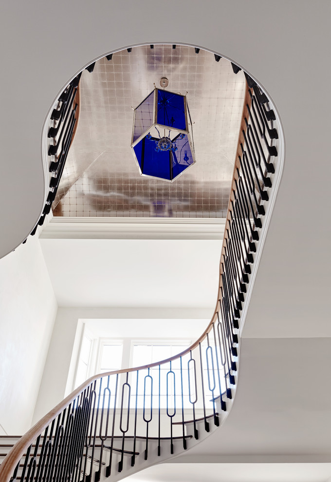 На фото: огромная изогнутая металлическая лестница в стиле неоклассика (современная классика) с деревянными ступенями