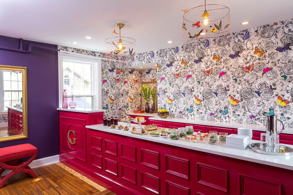 This is an example of an eclectic single-wall wet bar in Providence with red cabinets, quartzite benchtops, multi-coloured splashback, light hardwood floors and recessed-panel cabinets.