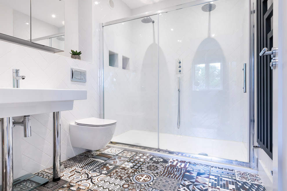 Modern master bathroom in Dublin with glass-front cabinets, a double shower, a wall-mount toilet, white tile, subway tile, white walls, porcelain floors, multi-coloured floor, a sliding shower screen, a niche and a freestanding vanity.