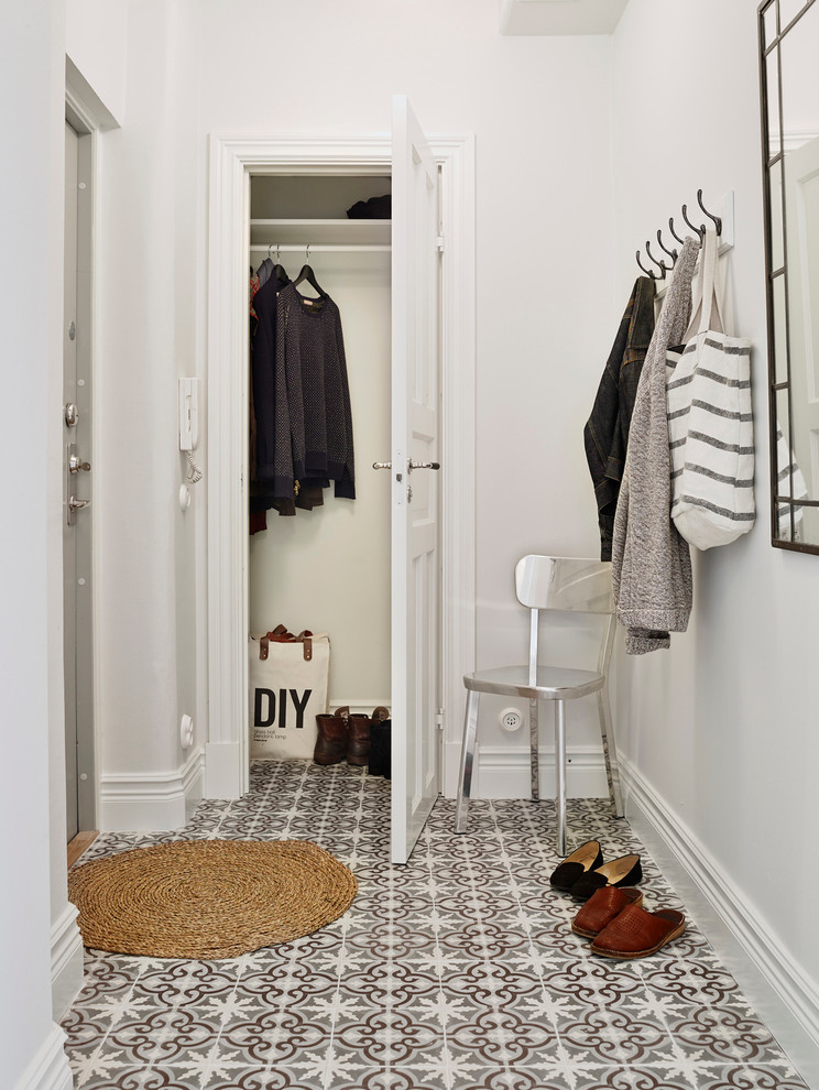 Design ideas for a mid-sized scandinavian entryway in Gothenburg with white walls and porcelain floors.