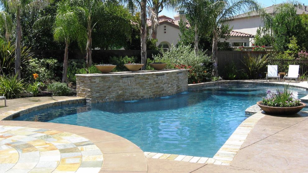 This is an example of a mediterranean backyard custom-shaped pool in Sacramento with concrete pavers.