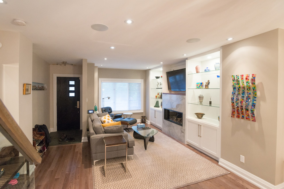 Mid-sized contemporary formal open concept living room in Toronto with beige walls, light hardwood floors, a ribbon fireplace, a metal fireplace surround, a wall-mounted tv and brown floor.