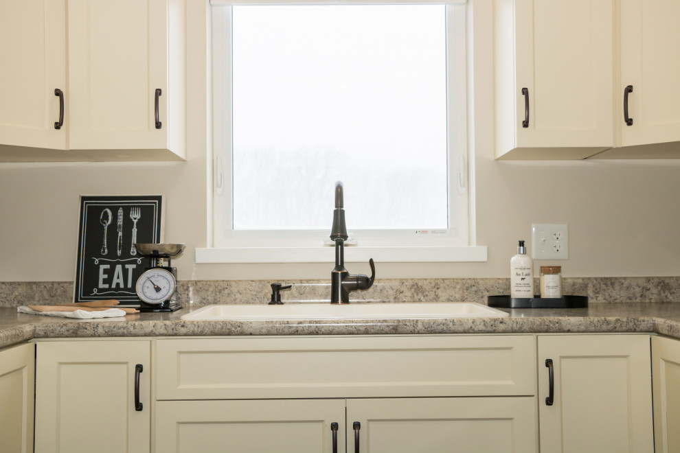 Example of a mid-sized u-shaped vinyl floor and brown floor kitchen design with a drop-in sink, recessed-panel cabinets, yellow cabinets, laminate countertops, stainless steel appliances, no island and brown countertops