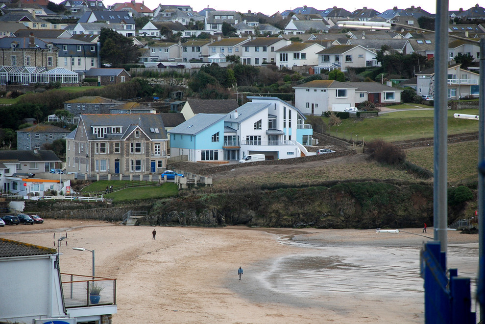 Expansive beach style split-level stucco white exterior in Cornwall with a butterfly roof, a tile roof and a grey roof.