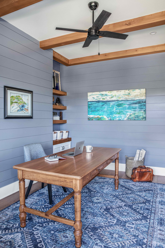 This is an example of a medium sized beach style study in Austin with blue walls, medium hardwood flooring, no fireplace, a freestanding desk, brown floors, exposed beams and tongue and groove walls.