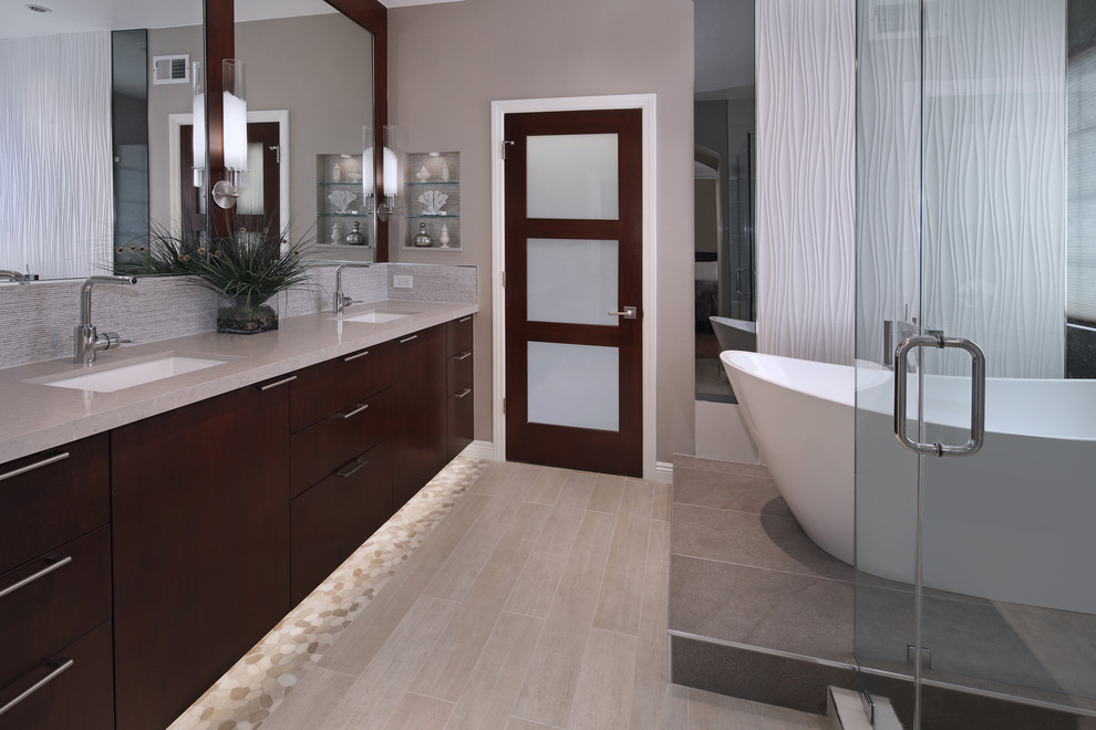 Photo of a large contemporary master bathroom in Orange County with flat-panel cabinets, dark wood cabinets, a freestanding tub, a corner shower, grey walls, porcelain floors, an undermount sink, granite benchtops, grey floor and a hinged shower door.