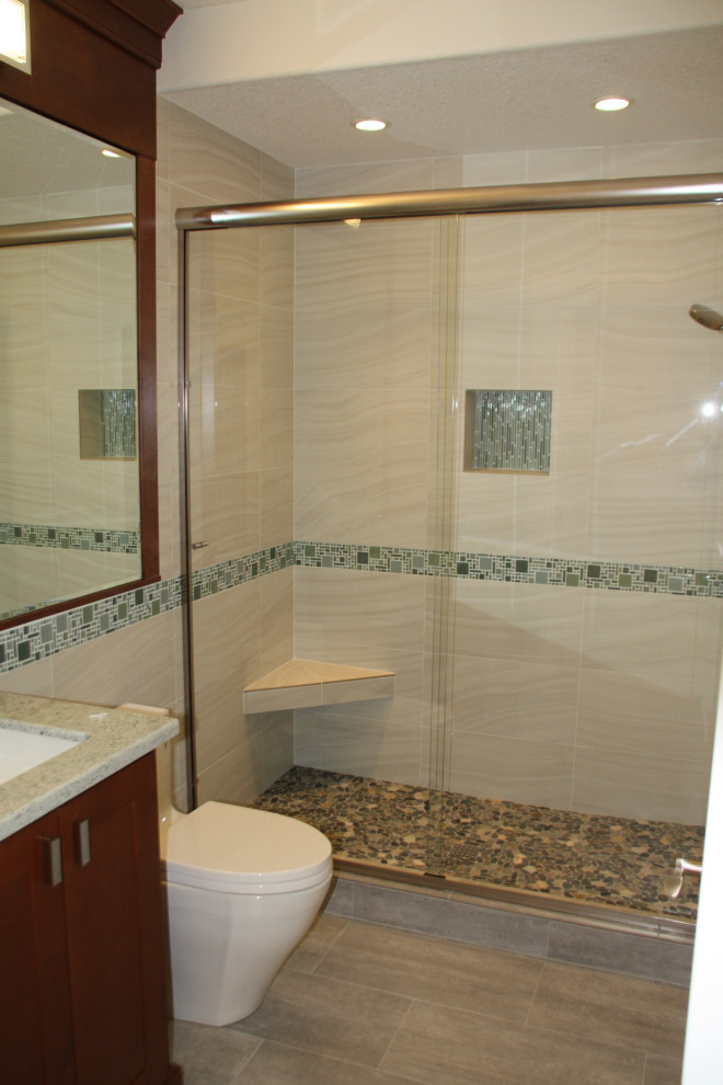 Источник вдохновения для домашнего уюта: ванная комната среднего размера в стиле кантри с фасадами в стиле шейкер, коричневыми фасадами, двойным душем, унитазом-моноблоком, серой плиткой, керамической плиткой, серыми стенами, полом из цементной плитки, врезной раковиной, столешницей из искусственного кварца, серым полом, душем с раздвижными дверями, разноцветной столешницей, сиденьем для душа, тумбой под одну раковину и встроенной тумбой
