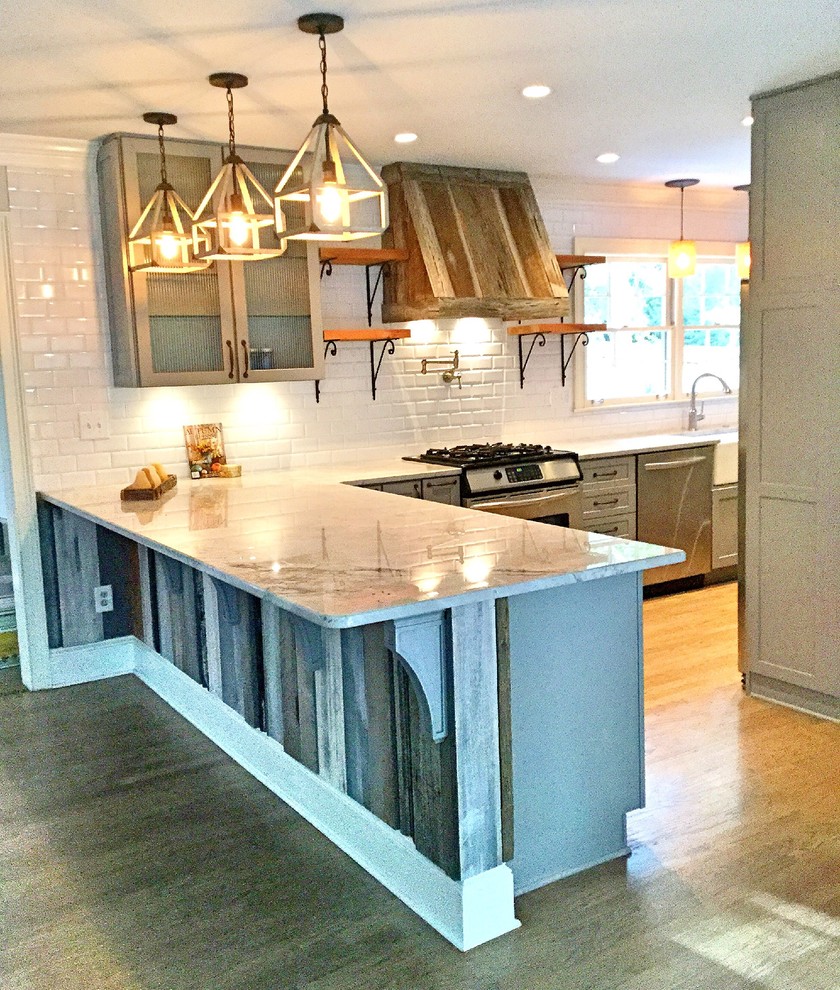 Mid-sized mountain style u-shaped light wood floor open concept kitchen photo in Atlanta with a farmhouse sink, shaker cabinets, gray cabinets, quartzite countertops, white backsplash, subway tile backsplash, stainless steel appliances and a peninsula