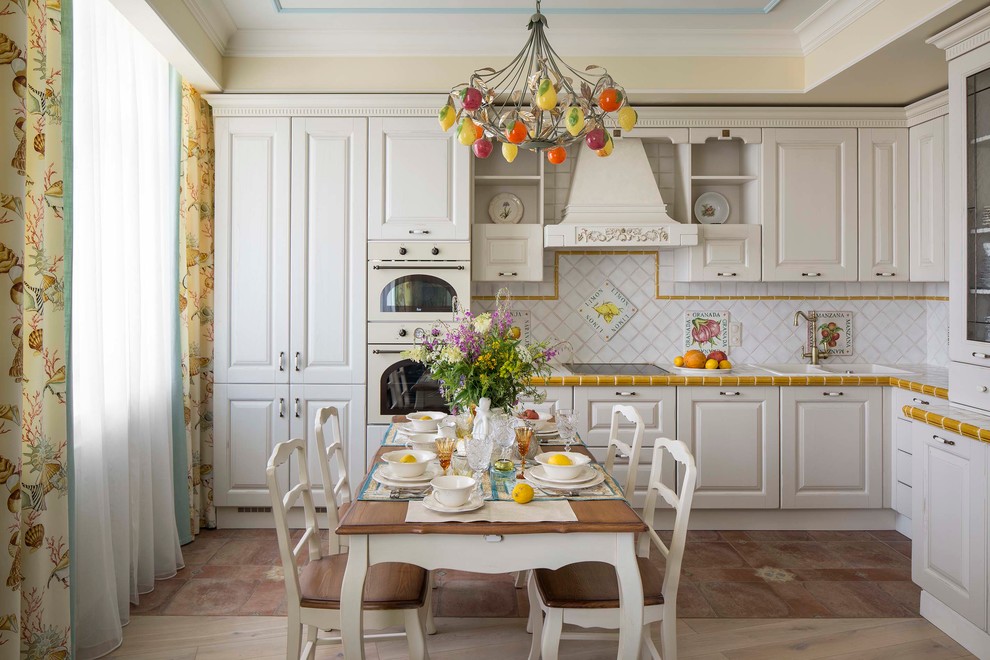 This is an example of a traditional l-shaped eat-in kitchen in Moscow with raised-panel cabinets, white cabinets, white splashback, white appliances and no island.